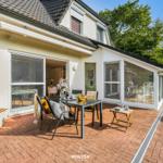 Terrasse mit Tisch, Stühlen und Blick in das Haus. Gartenbereich mit Pflanzen.