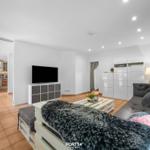 Wohnzimmer mit Sofa, Fernseher und Küchenbereich im Hintergrund.