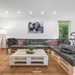 Wohnraum mit Sofa auf Paletten, Tisch und Wandbild.