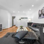 Wohnzimmer mit grauem Sofa, Fernseher und Wandbild.