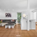 Wohnbereich mit Sofa, Couchtisch und Fitnessgerät. Wandbild und Holzboden.