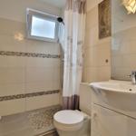 Badezimmer mit Dusche, Waschbecken und Toilette. Fliesen und Mosaikverkleidung.