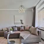 Wohnzimmer mit Sofa, Beistelltisch und moderner Deckenleuchte.