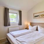 Schlafzimmer mit Doppelbett, Fenster und Wandbild.