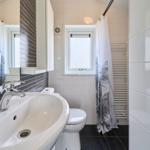 Badezimmer mit Waschbecken, Toilette und Duschbereich mit Fenster.