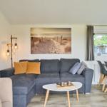 Wohnzimmer mit Sofa, Couchtisch und Essbereich. Wandbild und TV sichtbar.