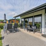 Terrasse mit Sitzgruppe, Grill und Gartentisch. Hinterhof mit Rasen und Hecken.