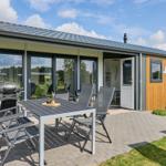 Terrasse mit Tisch, Stühlen und Grill. Eingang und Fenster sind sichtbar.