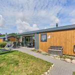 Moderne Ferienhaus mit Terrasse, Liegen und Grillplatz im Freien.