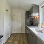 Küche mit Arbeitsplatte, Spüle und Fenster. Holzboden und graue Schränke.