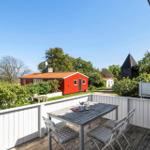 Terrace with table and chairs. View of red house and sea.