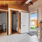 Utility room with washing machine, toilet, and shower. Outdoor view through open door.