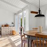 Dining area with wooden table, chairs, and windows to the outdoor terrace.