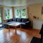 Wohnzimmer mit Sofa, Tisch und Fenstern zum Garten.