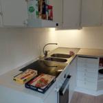 Küche mit Spüle, Herd und Schränken. Auf Arbeitsfläche liegen Nudelboxen.