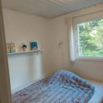 Schlafzimmer mit Bett, Fenster und Regal mit Dekoration.