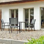 Terrasse mit Tisch und drei Stühlen vor einem Haus mit Schiebetüren.