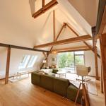 Wohnraum mit Holzdecke, Sofa und Fenster zur Außenterrasse.