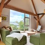 Wohnzimmer mit grünem Sofa, Holzrahmen und großem Fensterblick.