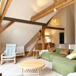 Wohnzimmer mit grünem Sofa, Holzrahmen und runden Tisch.