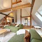 Wohnraum mit grünem Sofa, Holzrahmen und Dachfenster.