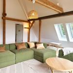 Wohnraum mit grünem Sofa, Holzrahmen und Dachfenstern.