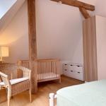 Kinderzimmer mit Babybett, Wickelstuhl und Kleiderschrank unter Dachschrägen.