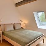 Schlafzimmer mit Dachfenstern, Holzbett und Nachttischen mit Lampen.