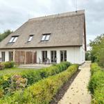 Haus mit Strohdach, Terrasse und gepflegtem Gartenweg.