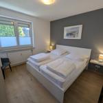 Schlafzimmer mit Doppelbett, Fenster und Holzboden.