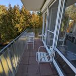 Terrasse mit Tisch, Stühlen und Blick auf Bäume.