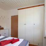 Schlafzimmer mit Bett, Kleiderschrank und Fenster mit Katzenfigur.
