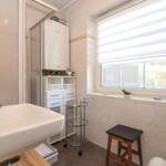 Badezimmer mit Waschbecken, Dusche, Fenster und Stuhl.