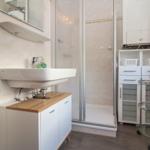 Badezimmer mit Dusche, Waschbecken und Aufbewahrungsmöbel.
