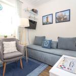 Wohnzimmer mit Sofa, Sessel, Fernseher und Wandbildern.