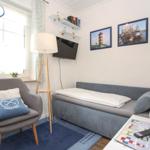 Ein Schlafzimmer mit Sofa-Bett, Sessel und Fernseher an der Wand.