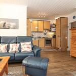 Wohnzimmer mit Sofa, Küchenbereich und Holzmöbel