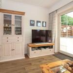Wohnzimmer mit Fernseher, Schrank und Blick auf den Garten.
