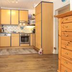 Küche mit Holzmöbeln, Edelstahlgeräten und Fliesenwand.
