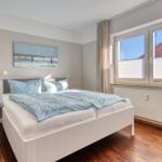 Schlafzimmer mit Doppelbett, Wandbild und Fenster mit Blick.