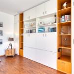 Zimmer mit integriertem Schrank, Wandbildern und Holzboden.