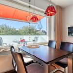 Esszimmer mit Tisch, Stühlen und Balkonansicht. Deckenleuchte und Fernseher.