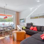 Wohnzimmer mit Sofa, Esstisch und Blick auf Balkon