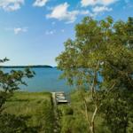 Hafen mit Booten an ruhigem See unter blauem Himmel mit Bäumen