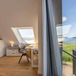 Dachgeschosszimmer mit Schreibtisch und Blick auf See