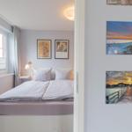 Schlafzimmer mit Doppelbett, Fenster und Wandbildern.