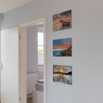 Durchgang mit Tür zur Schlafzimmer und drei Wandbildern mit Meeresmotiven.