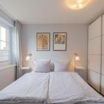 Schlafzimmer mit Doppelbett, Fenster und weißen Schwebetüren.