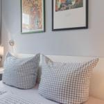 Schlafzimmer mit Bett, Kissen und Wandbildern.