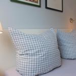 Ein Bett mit karierten Kissen und Wandlampen.